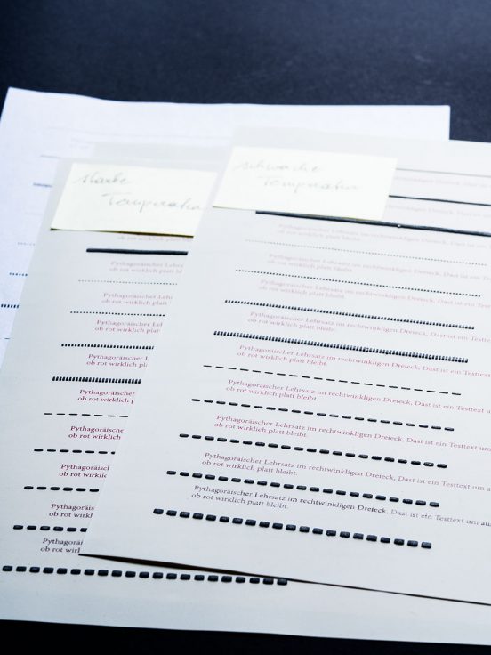 Pages of swell paper with test lines in different line styles and red writing in different shades that has stayed flat in the swelling process